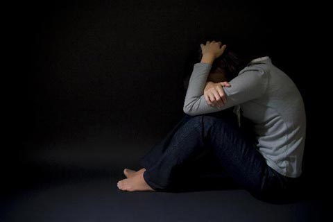 
	한 여성이 어두운 곳에서 웅크리고 앉아 불안해하고 있다. 
