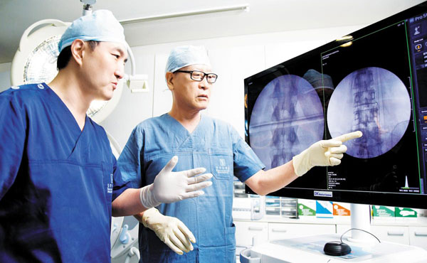 척추관 협착증의 80%는 비수술 치료로 증상을 낫게 할 수 있다. 김영수병원의 김영수(오른쪽) 병원장과 척추센터 임대철 소장이 척추관 협착증 환자의 검사 사진을 보며 치료법을 논의하고 있다.