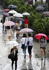 비 오는 날 사람들이 우산을 쓰고 걸어가고 있다