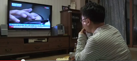 남자가 야식을 먹으면서 TV를 보고 있다.