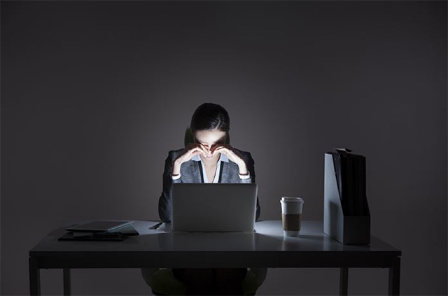 어두운 방 안 컴퓨터 앞에 한 여자가 고개를 숙이고 앉아 있는 모습이다