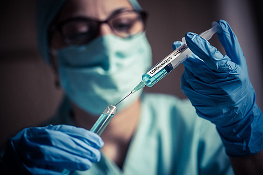 한 여성 의료진이 코로나 백신을 주사기로 옮기고 있다