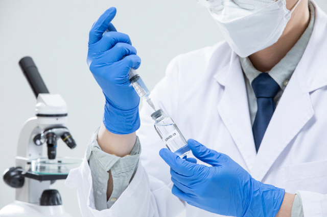실험실에서 한 남성이 코로나19 백신을 주사기로 옮기고 있다