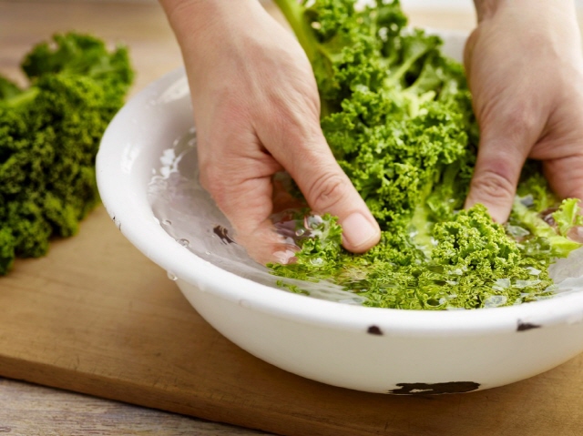 그릇에 담긴 녹색 채소를 씻고 있는 손