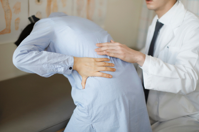허리 아파하는 여성 뒷모습과 의사