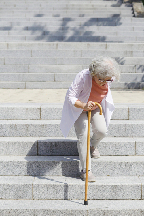 지팡이를 잡고 계단을 오르는 노인 여성