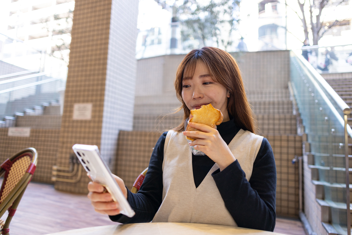 휴대전화 보며 간식 먹는 여성