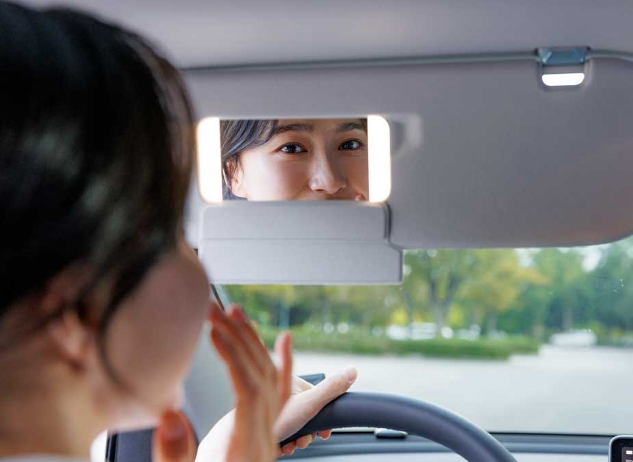 차에서 거울 보는 여성