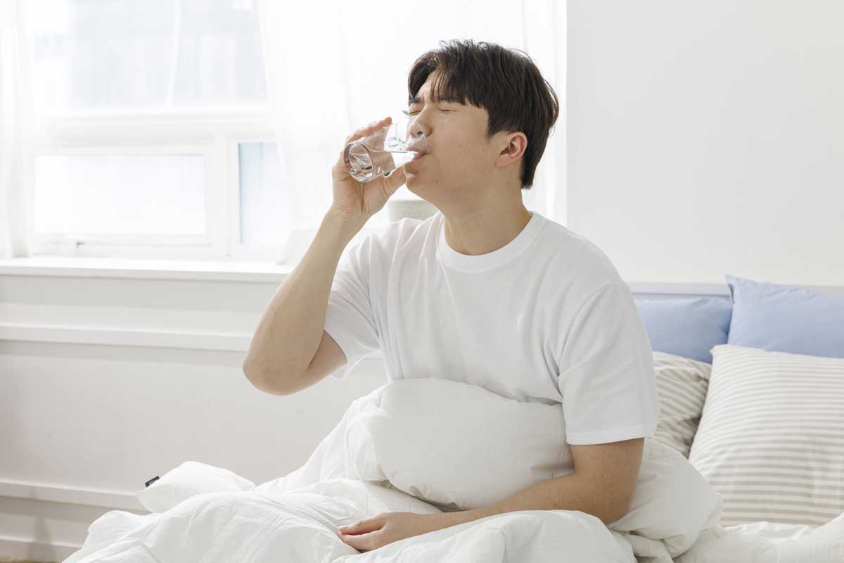 침대에서 물 마시는 사람